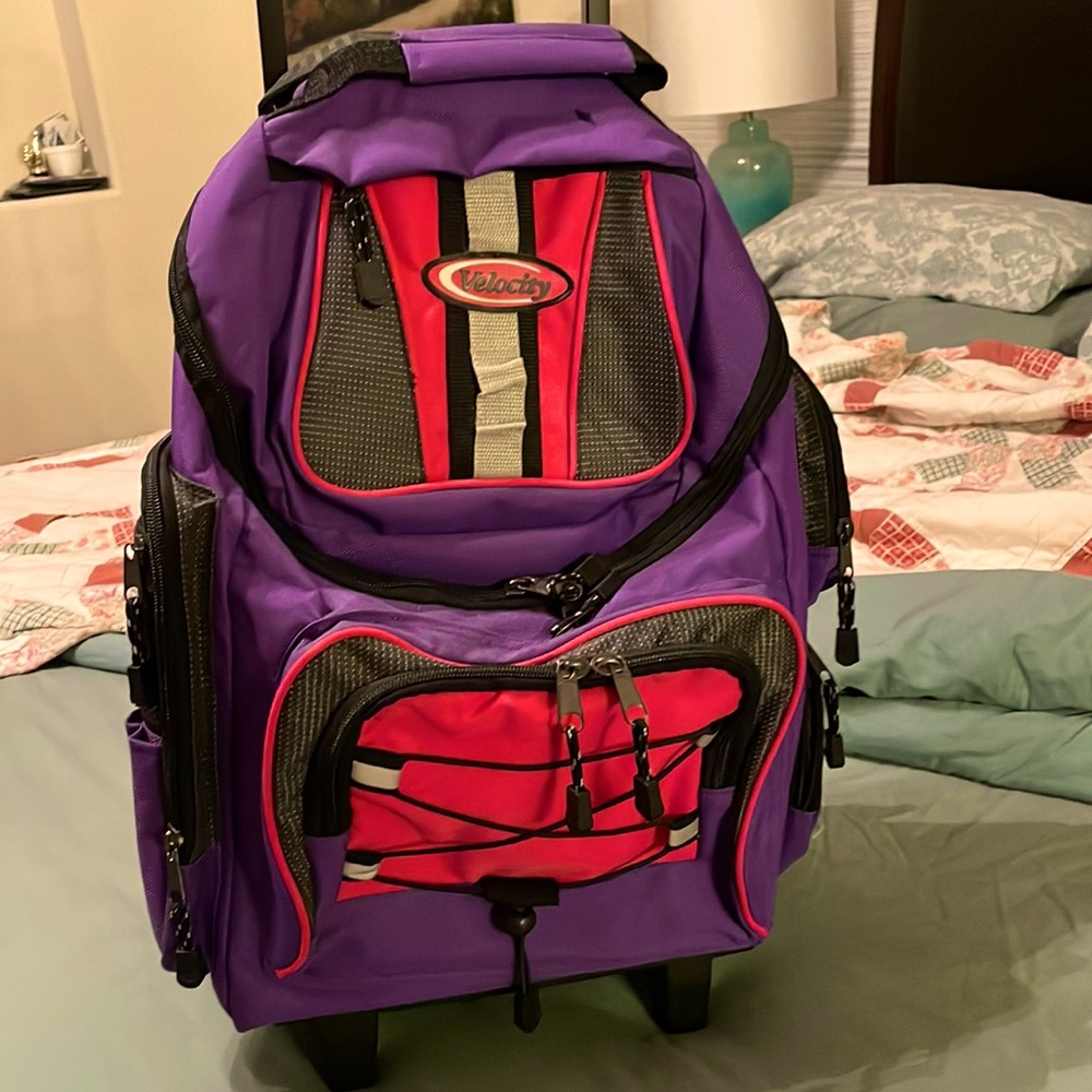 Velocity backpack with wheels and handle in purple with pink accents.